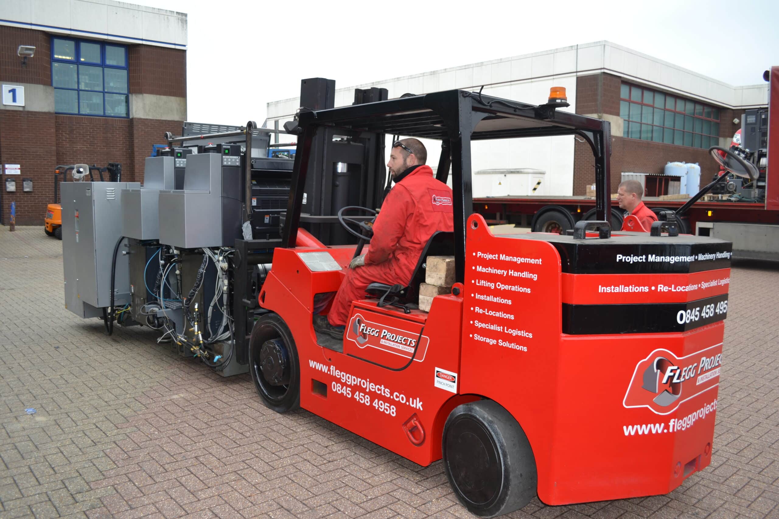 red forklift being driven by operator