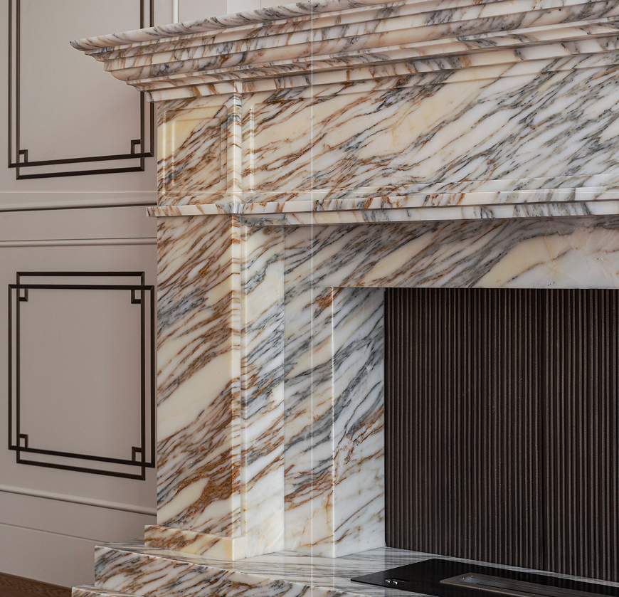 Luxury fireplace in veined marble with detailed surround and dark fire insert