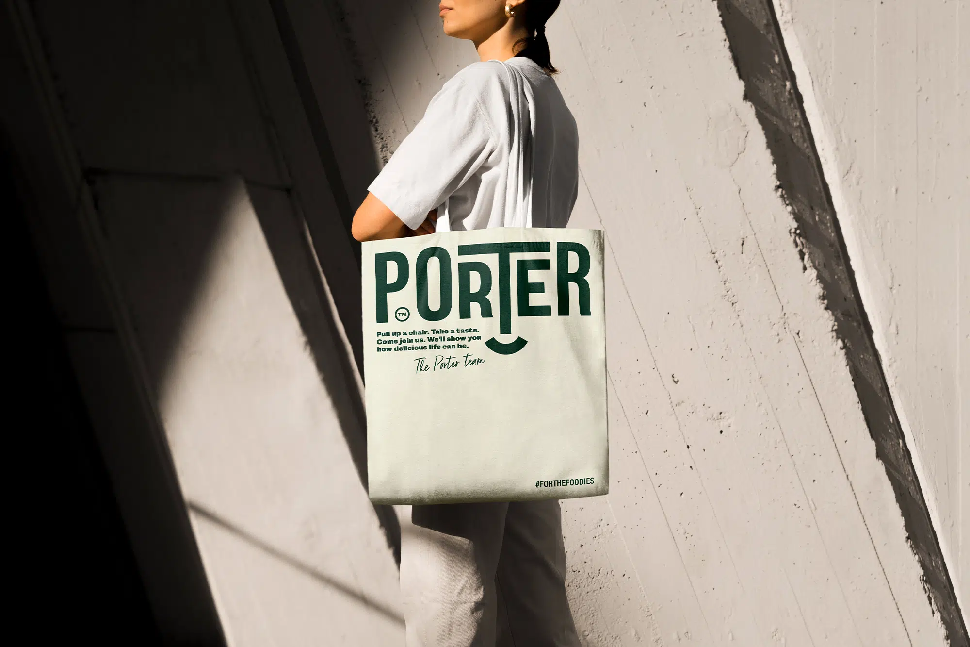 Person carrying a Porter tote bag with bold logo design.