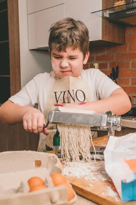 Young boy making pasta at home, showcasing love for food.
