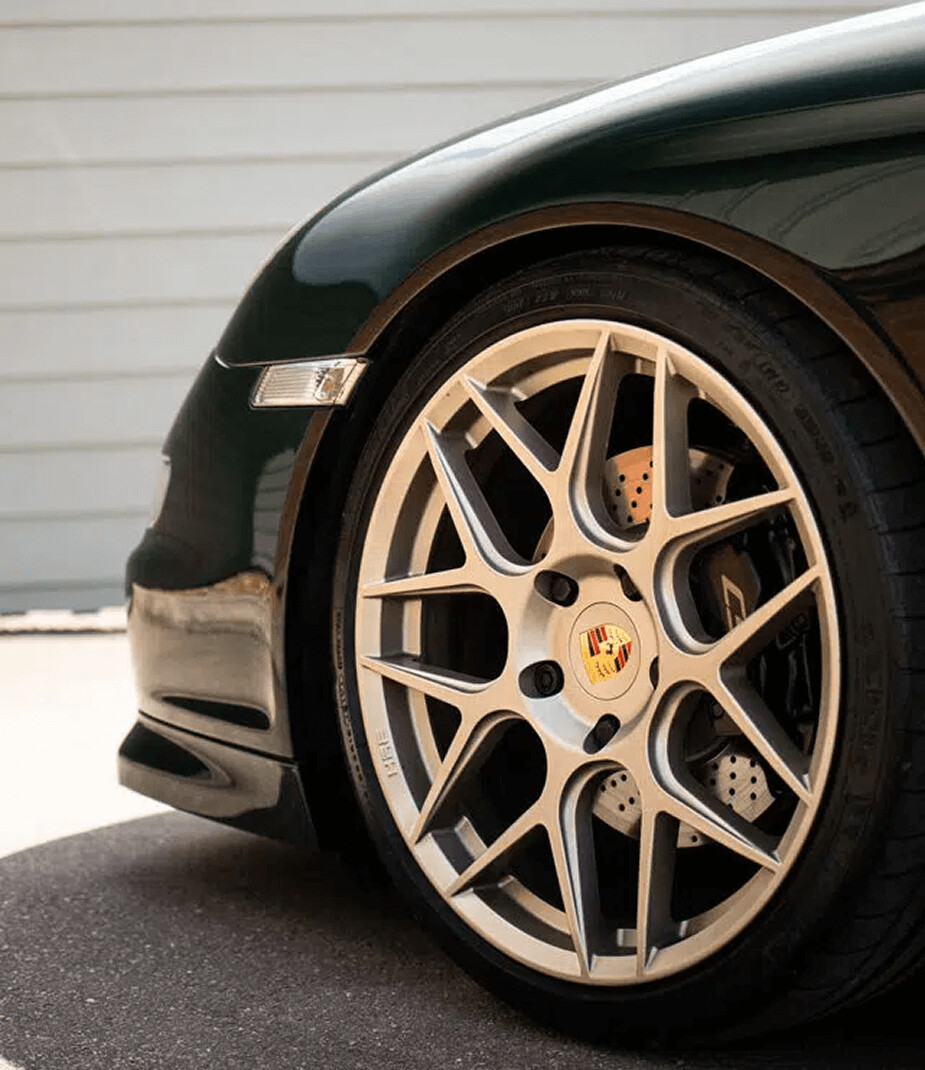 Close-up of a Porsche sports car wheel with silver alloy rims.