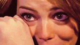 A close-up GIF of Emma Stone looking emotional with teary eyes, expressing feelings of joy and relief.