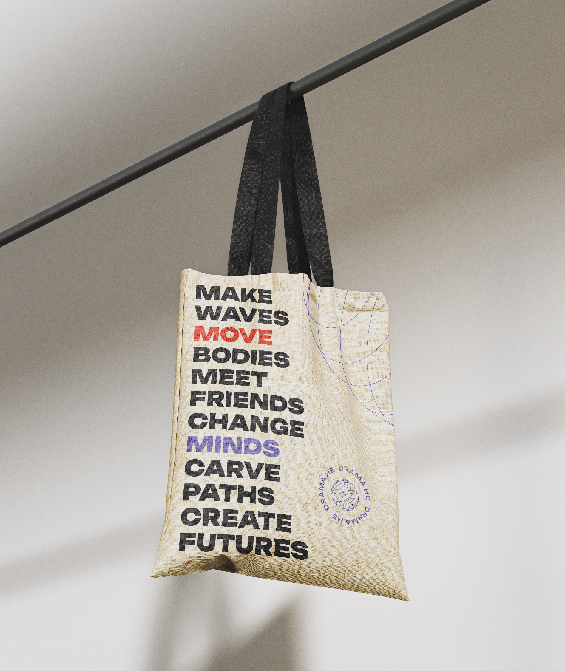 A branded DramaHE canvas tote bag with a typographic design of their core mission statements hanging from a rail.