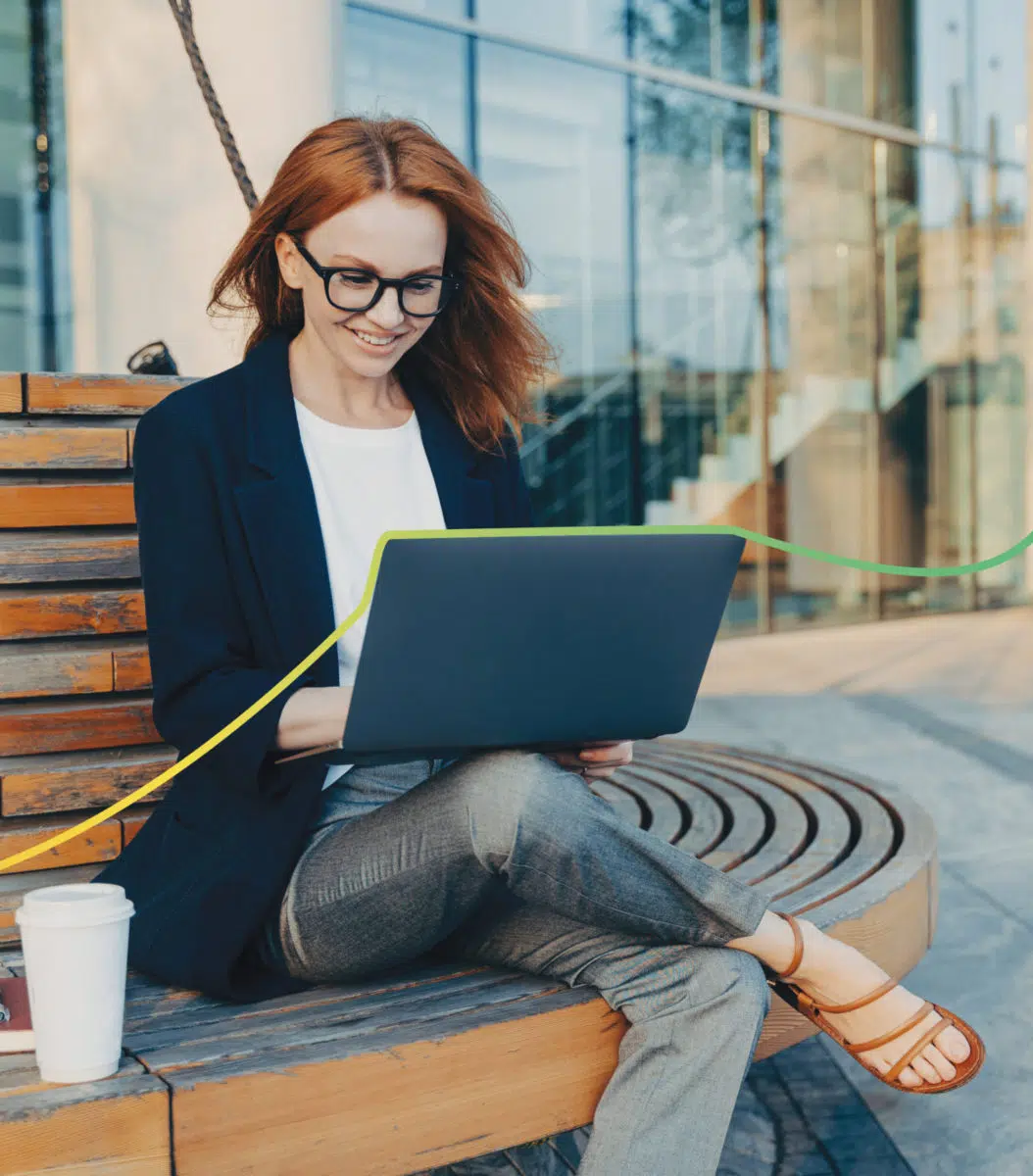 Young professional woman sitting outdoors with a laptop