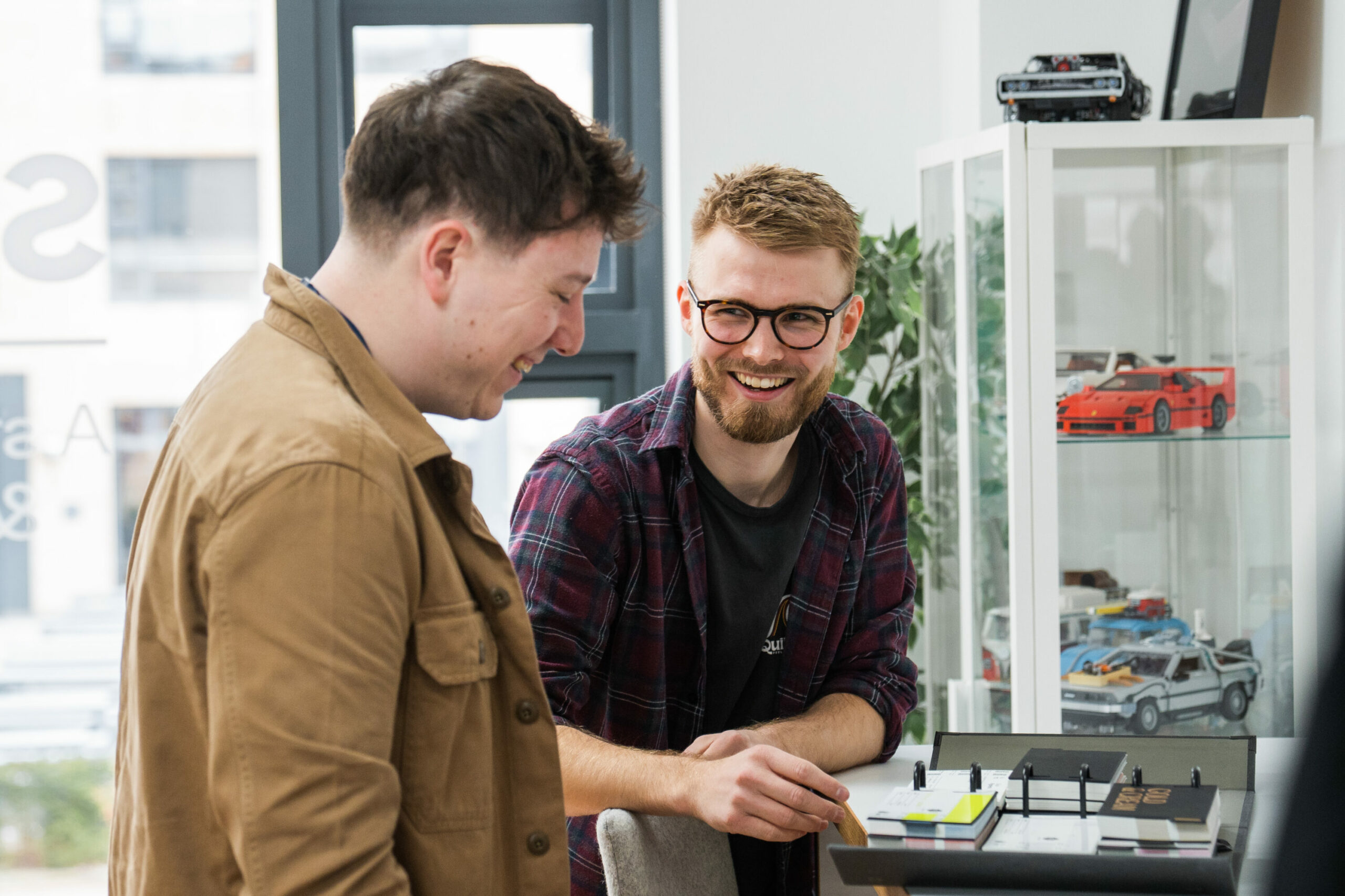 Two Stratos colleagues collaborating and laughing during a creative review in the office.