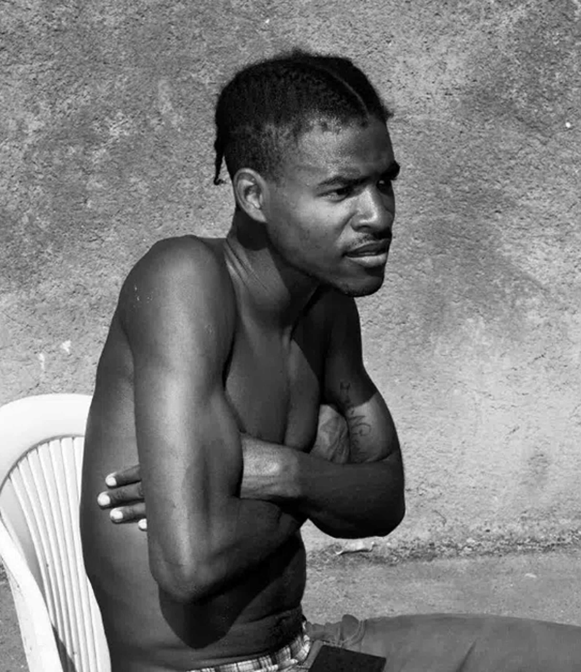 Black-and-white photo of a young man sitting with arms crossed.
