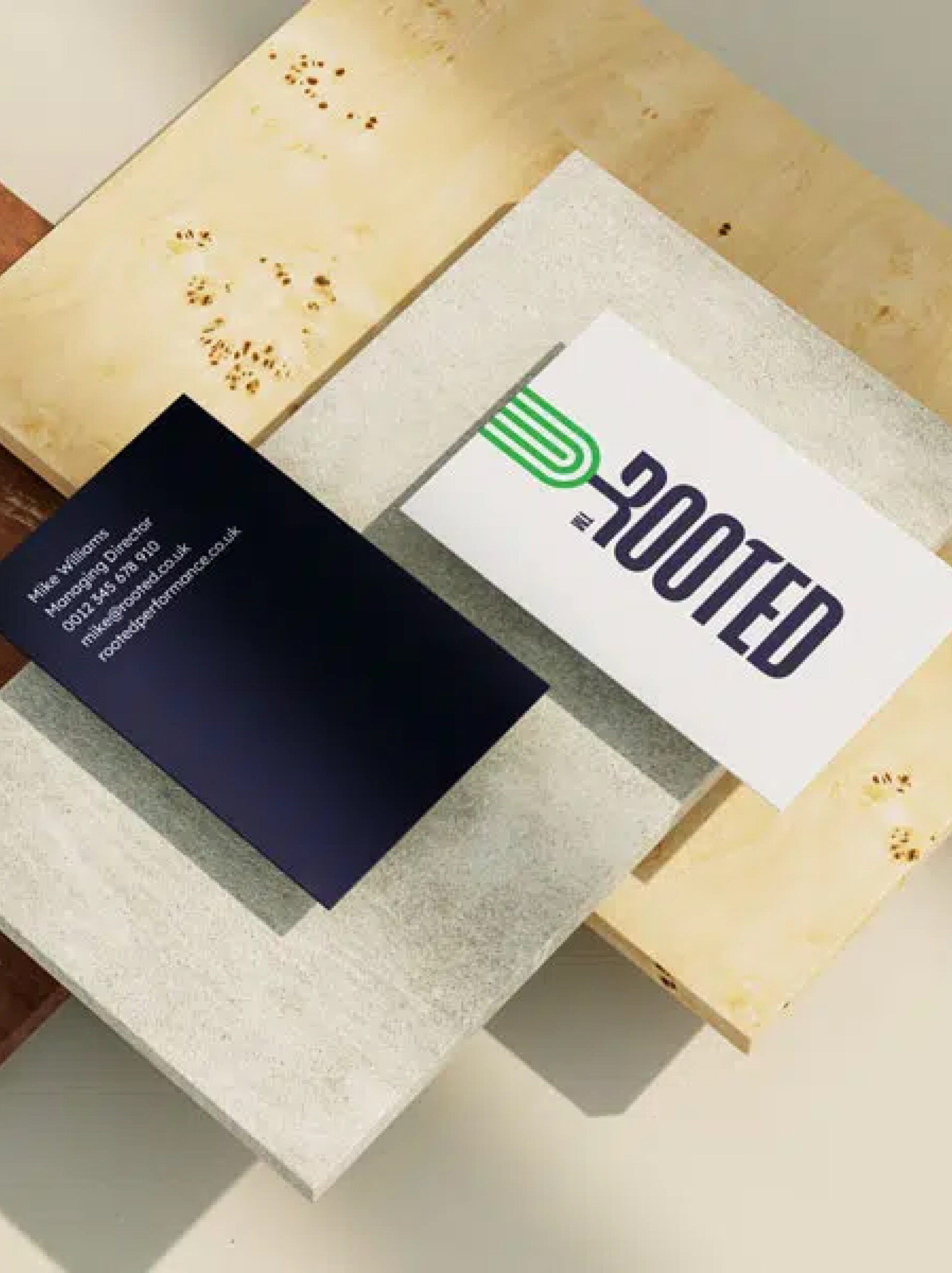  The front and back of the Rooted business card, showcasing the brand's logo and professional stationery design.
