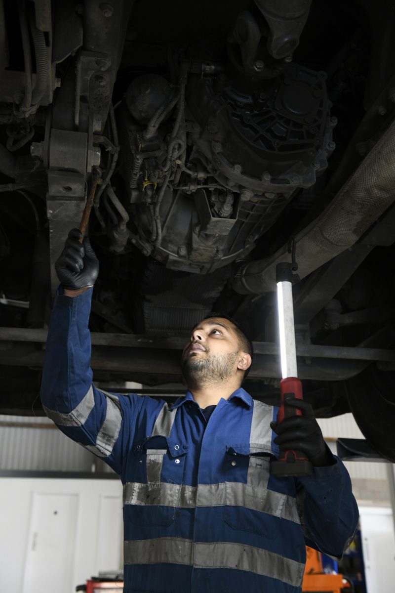 Mechanic inspecting and cleaning a vehicle’s brake disc at an Enterprise Flex-E-Rent service center.