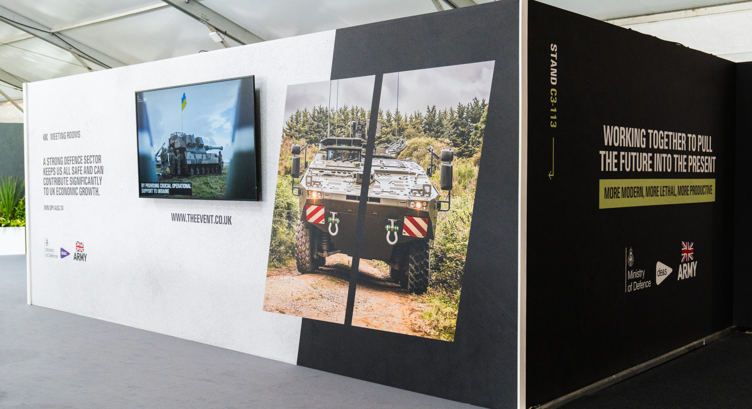 Close-up of display wall featuring armoured vehicle imagery and event branding.