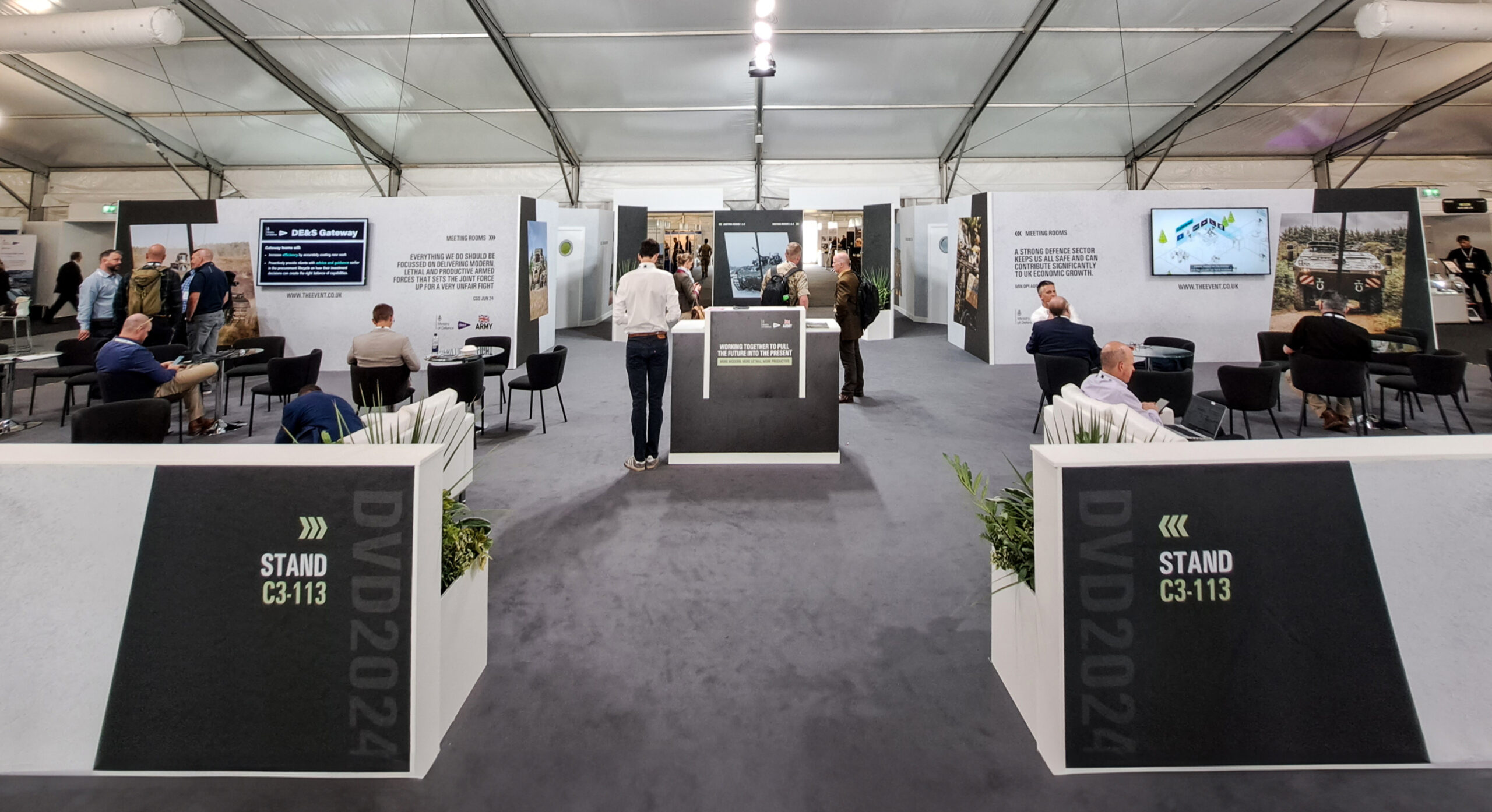Defence exhibition stand with attendees engaging in discussions.
