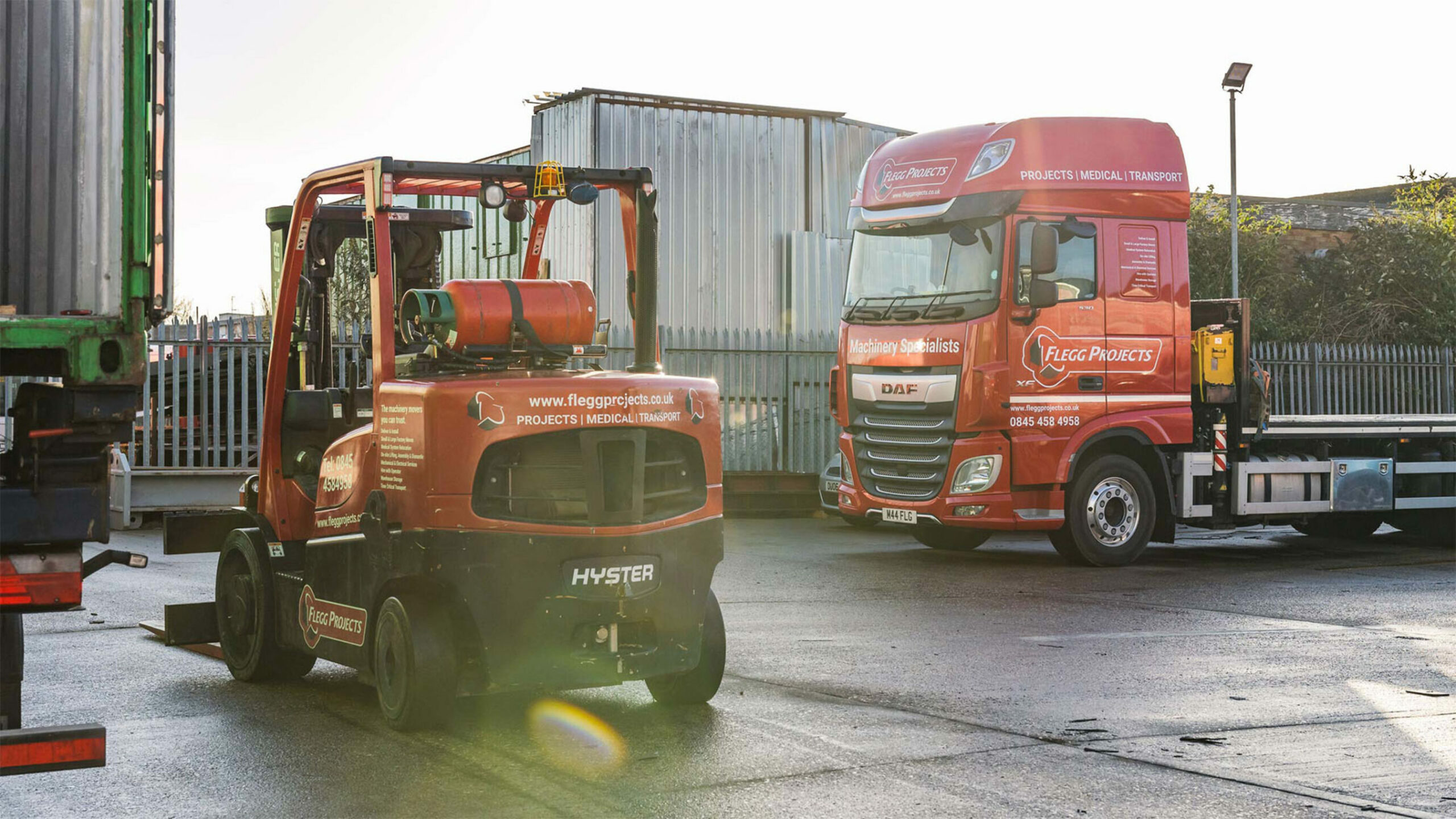 Flegg Projects branded forklift and truck in a yard.