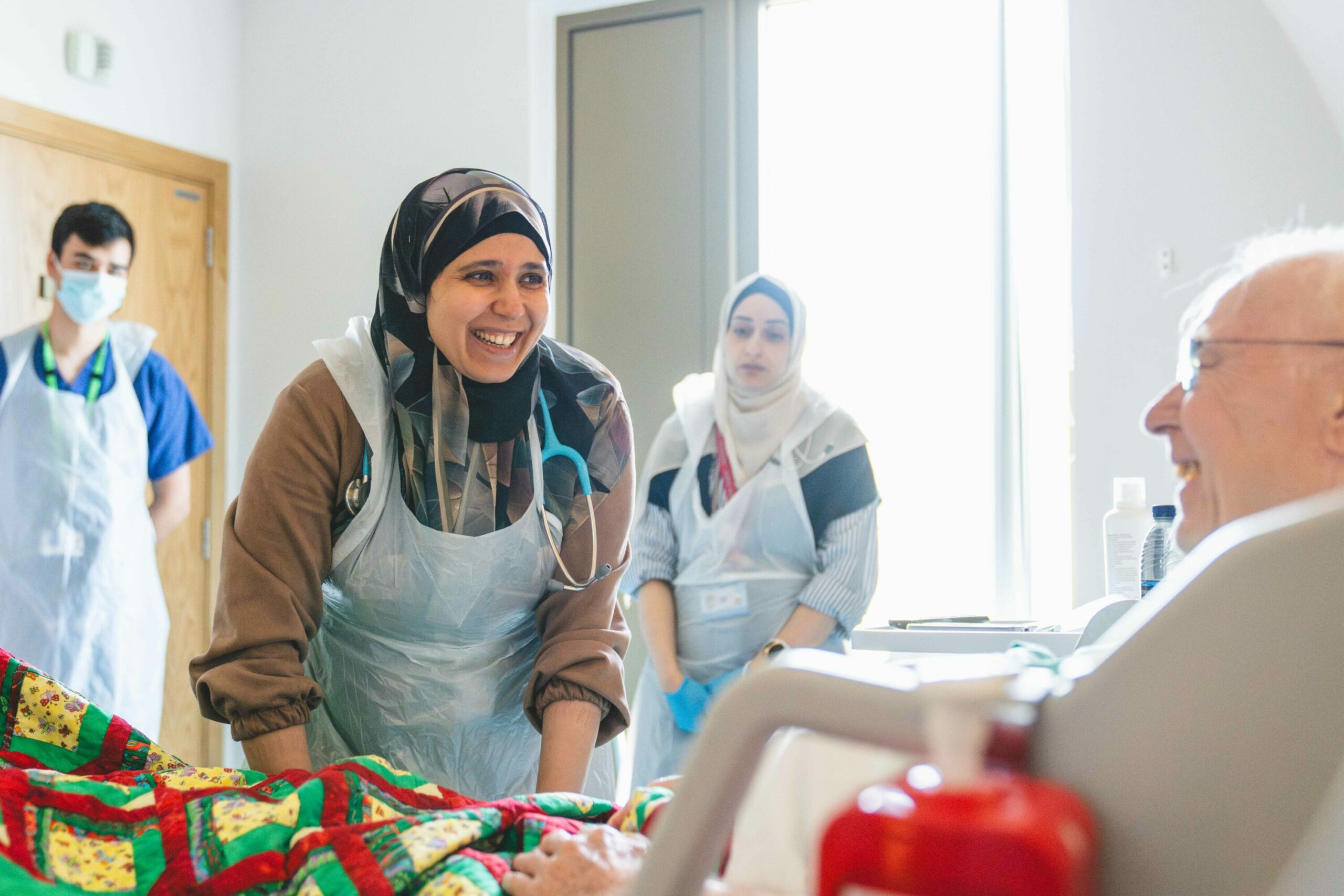 Smiling doctor interacting with an elderly patient in a hospital ward.