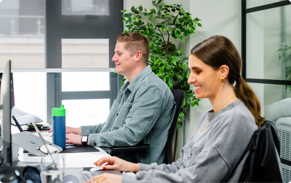 Stratos team members Jack and Meg working collaboratively at their desks, showcasing the agency's positive office environment.