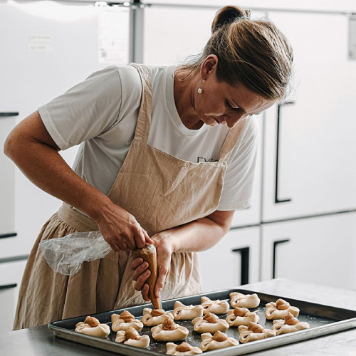 Baker piping pastry dough onto a tray.