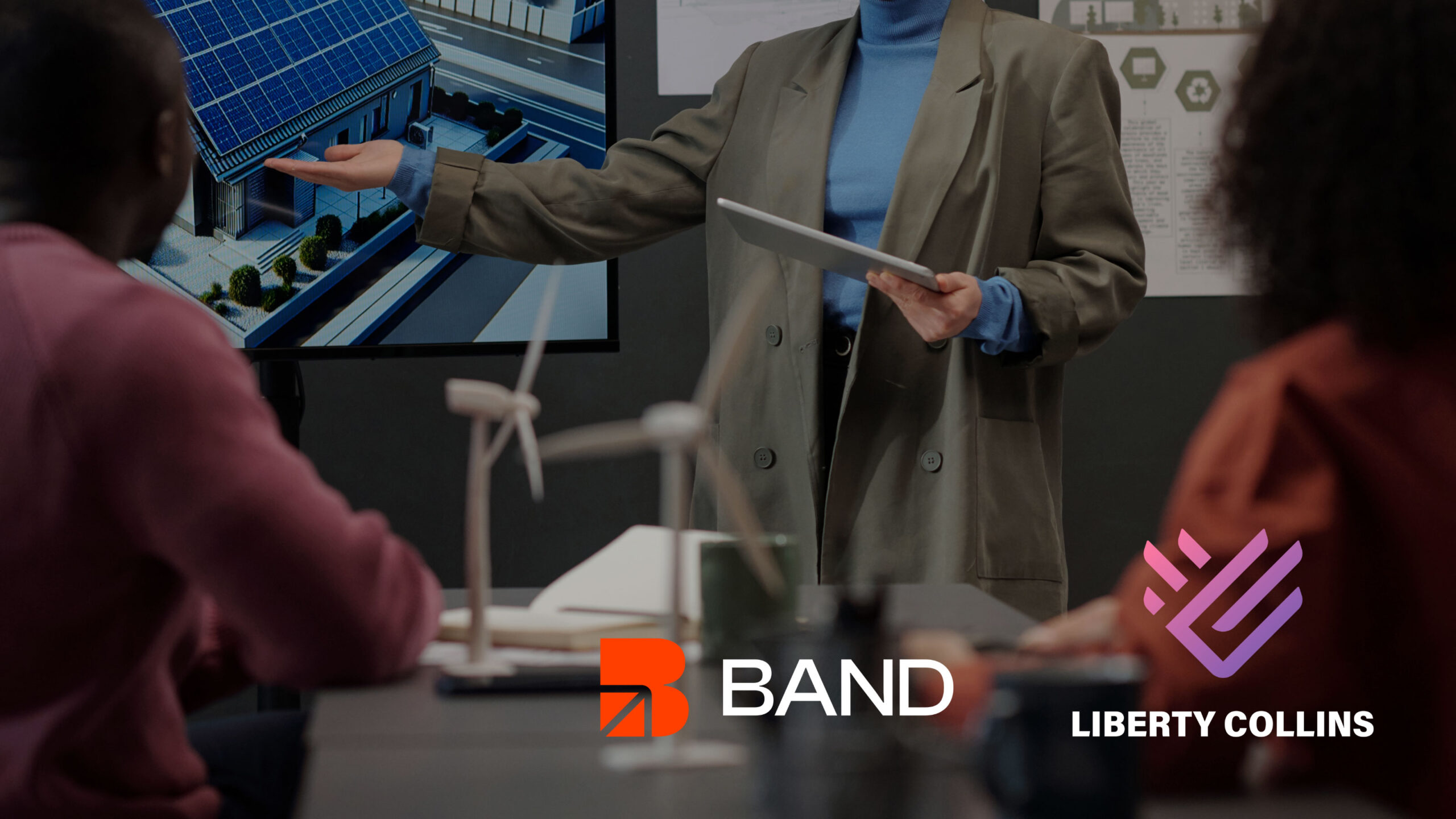 Woman presenting presentation to colleagues and BAND and Liberty Collins Logos