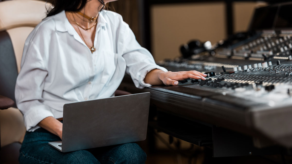 Cropped view of sound producer working at laptop and deck