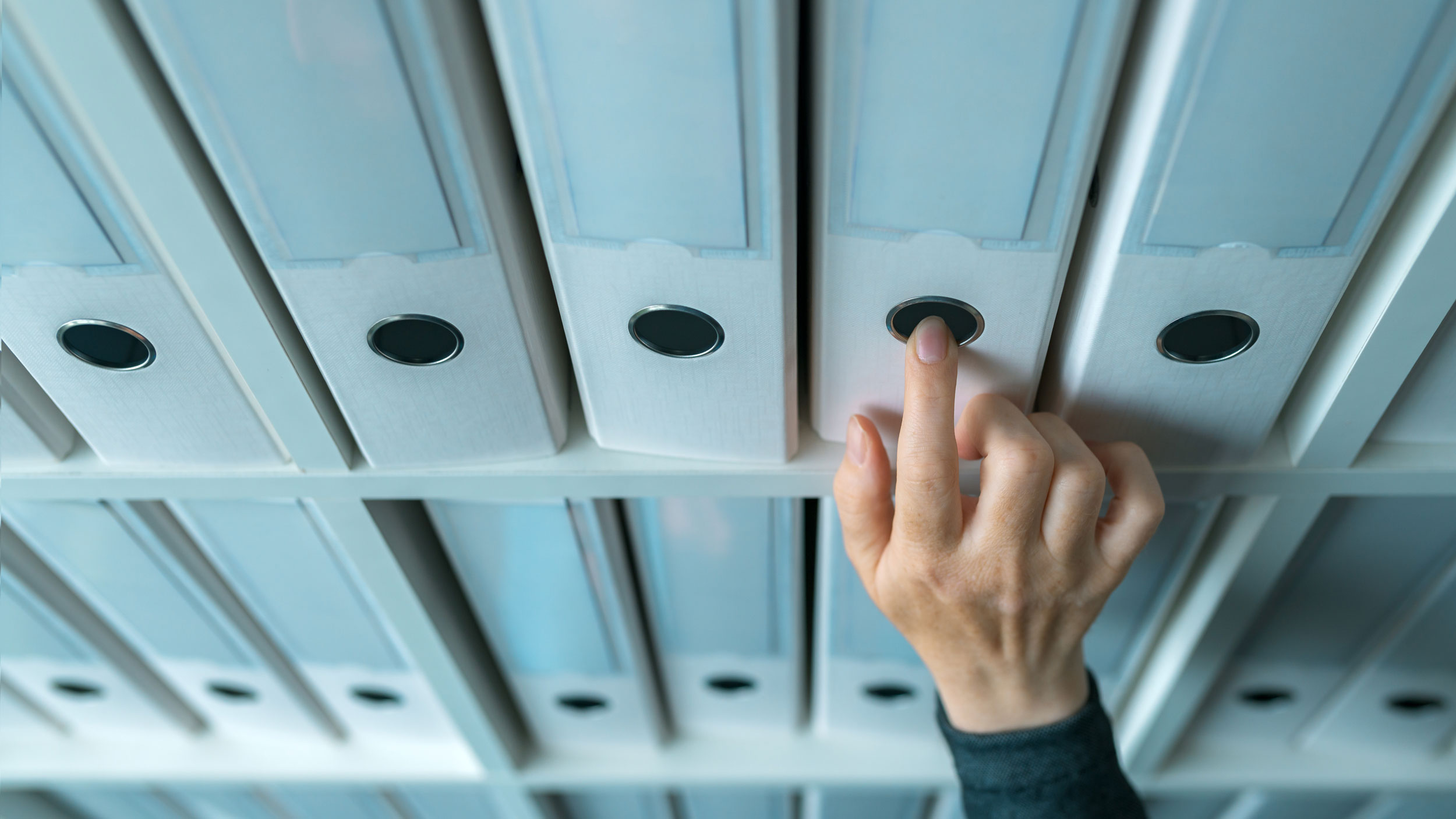hand-selecting-a-file-folder-from-shelves