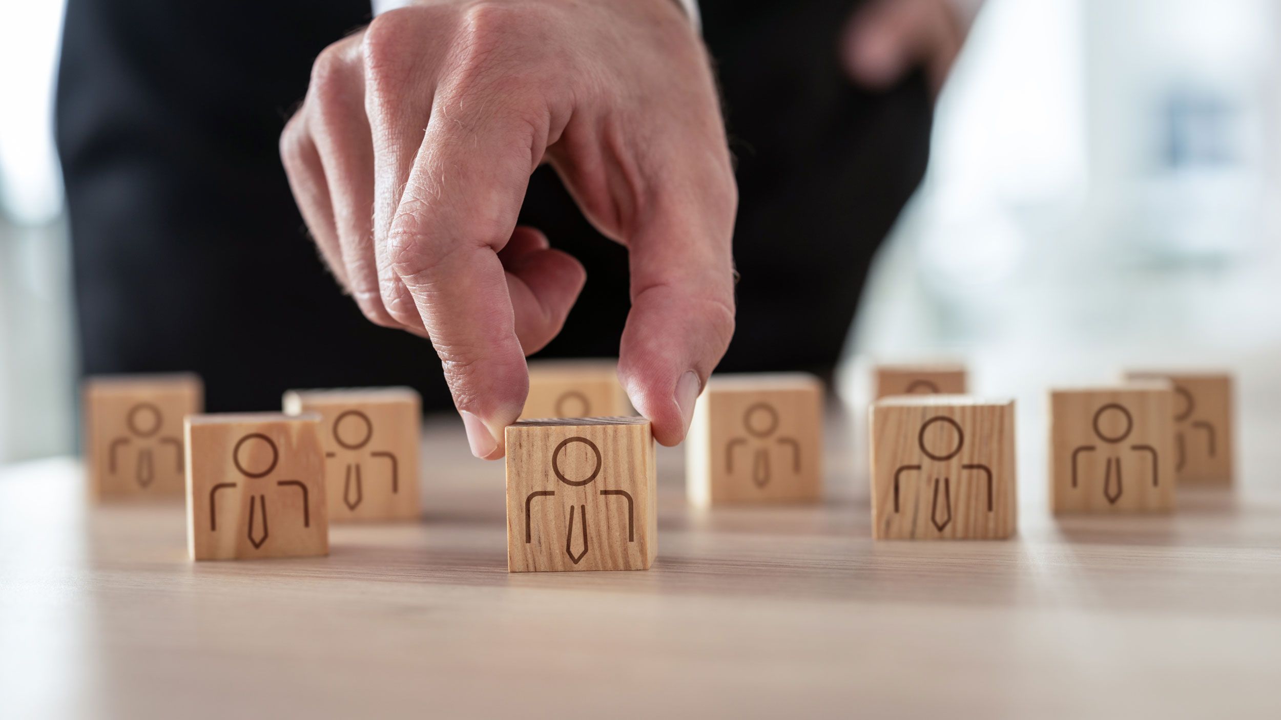 professional hand selecting colleague from wooden blocks