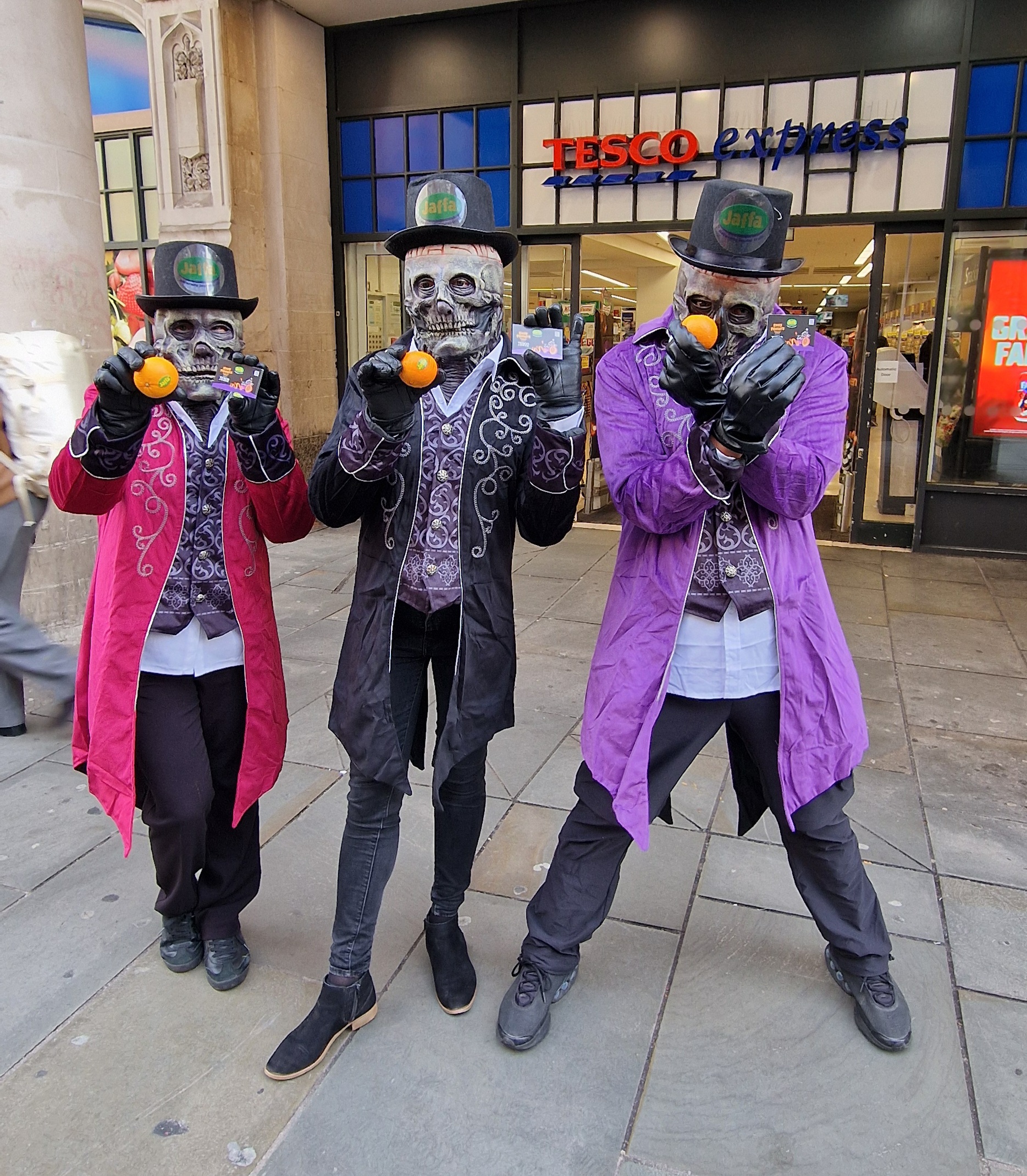 people dressed as skeletons holding oranges