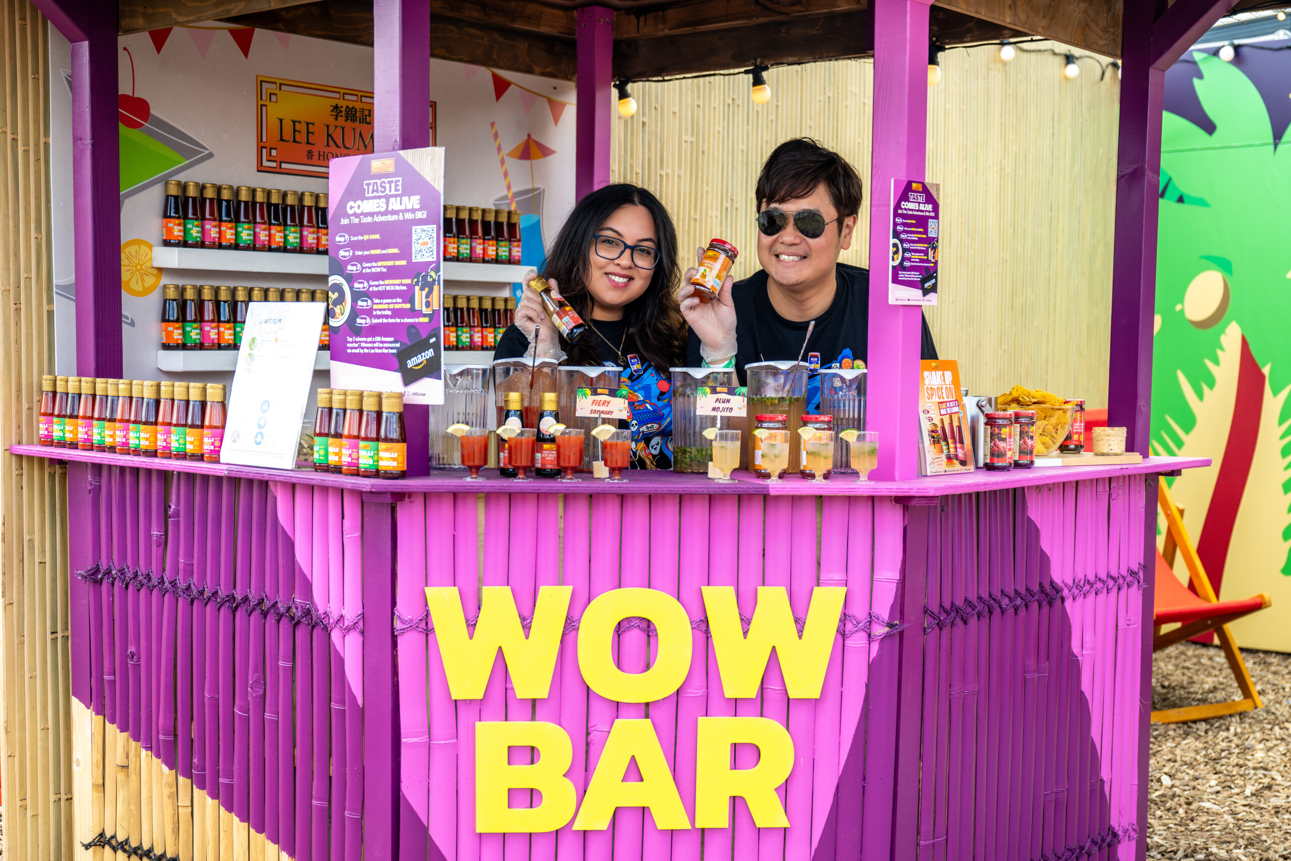 two smiling people behind a pink bar counter